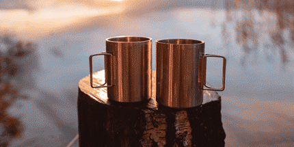 two stainlesss steel mugs sunset