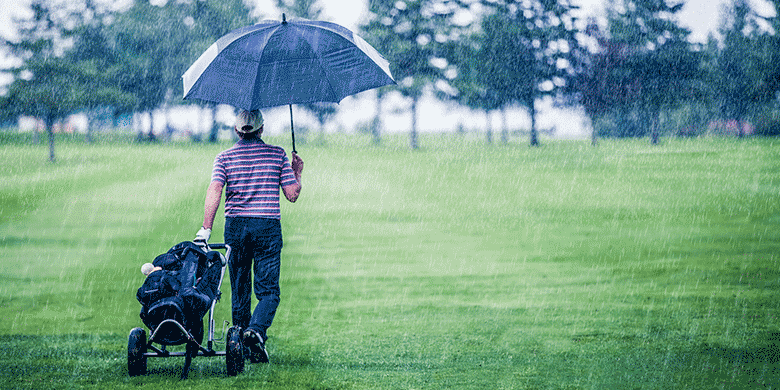 man playing golf holding umbrella
