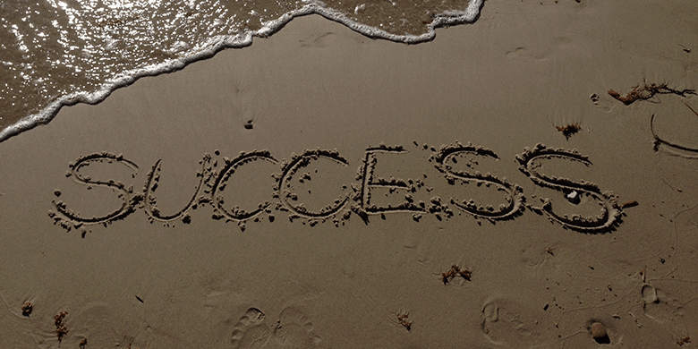 Success written in the sand on the shore of a beach