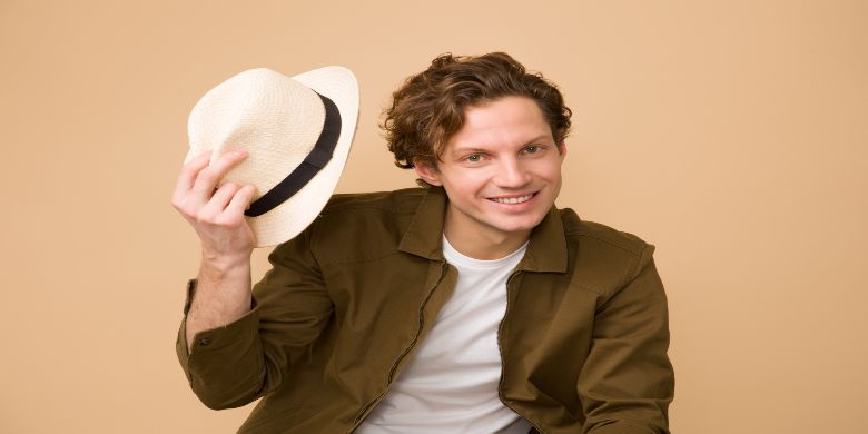 A guy tipping his hat to greet someone.