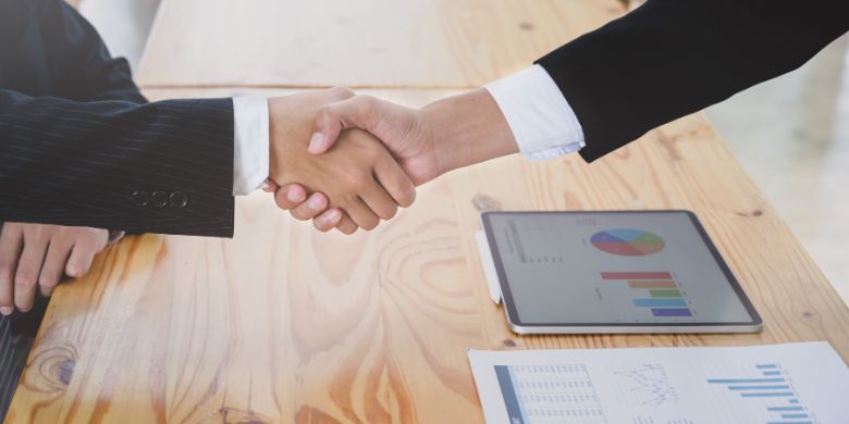 Two people shaking hands after just negotiating a deal.