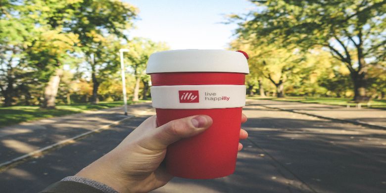 A travel mug in someones hand.