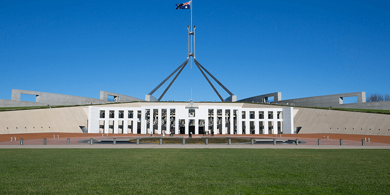 The Australian flag blowing in the wind attached to the top of Parliament House