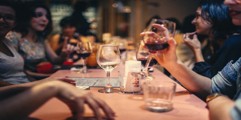 A dinner party with people holding wine glasses.