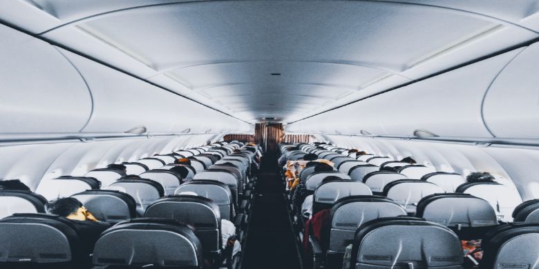 The cabin of a commercial airline plane with people in their seats.