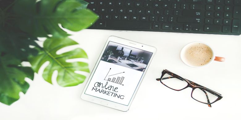 A desk with a coffee and a phone screen which mentions online marketing.