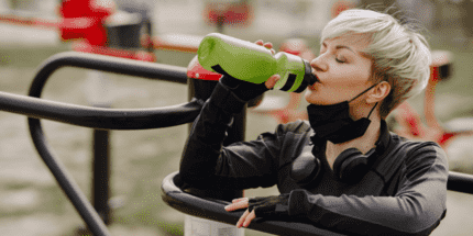 woman drinking from a plastic sports bottle