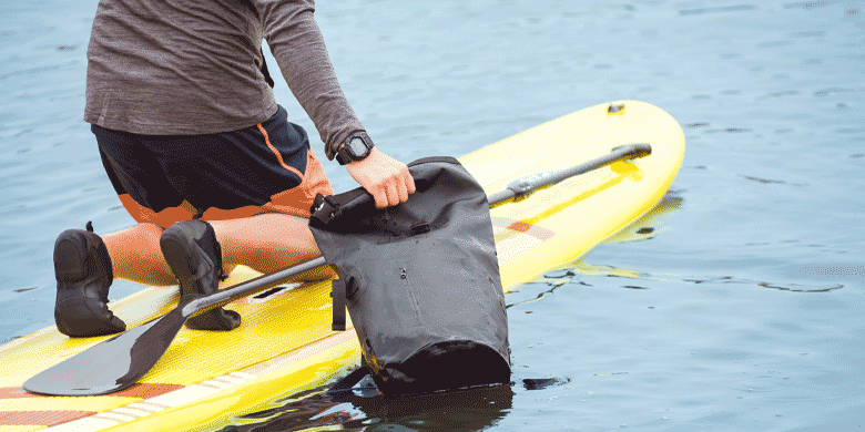 paddle boarder using a dry bag 