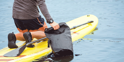 paddle boarder using a dry bag 