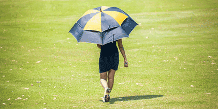 woman on golf course with umbrella