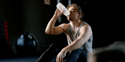 man at gym drinking from water bottle